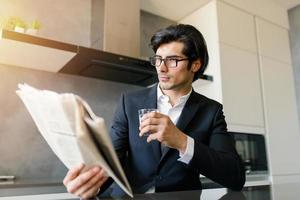 zakenman lezen nieuws van een krant- terwijl drinken een koffie Bij huis foto