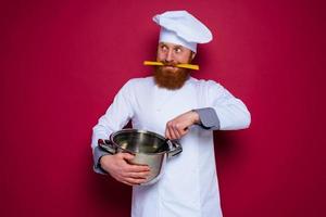 gelukkig chef met baard en rood schort is klaar naar koken foto