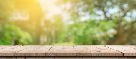 leeg hout tafel en onscherp bokeh en vervagen achtergrond van tuin bomen met zonlicht. Product Scherm sjabloon. foto