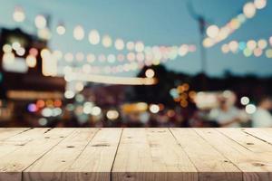 leeg houten tafel en wazig achtergrond Bij nacht markt festival mensen wandelen Aan weg met kopiëren ruimte, Scherm montage voor Product. foto