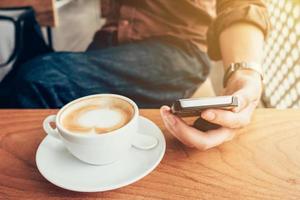 hand- Mens gebruik makend van telefoon in koffie winkel met wijnoogst filter. foto