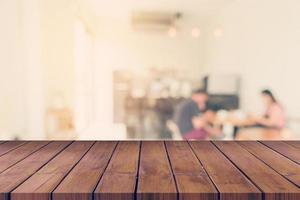 leeg hout tafel en wazig achtergrond klant Bij koffie winkel vervagen achtergrond met bokeh, wijnoogst afgezwakt. foto
