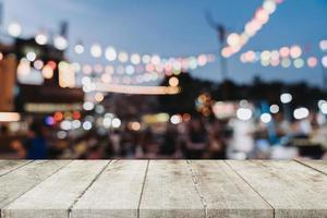 leeg houten tafel en wazig achtergrond Bij nacht markt festival mensen wandelen Aan weg met kopiëren ruimte, Scherm montage voor Product. foto