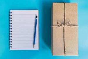 top visie bruin geschenk doos en notitieboekje papier voor nieuw jaar Aan blauw pastel kleur achtergrond. foto