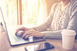 bedrijf vrouw gebruik makend van laptop computer Doen online werkzaamheid Aan hout tafel Bij huis kantoor. foto