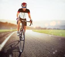 fietser racing Aan de weg Bij zonsondergang foto