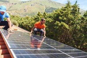 arbeiders monteren energie systeem met zonne- paneel voor elektriciteit en heet water foto