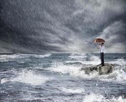 zakenman met paraplu gedurende storm in de zee. concept van crisis foto