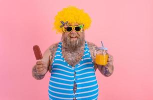 dik gelukkig Mens met baard en pruik eet een ijslolly en drankjes een sap fruit foto