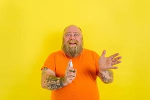 gelukkig Mens met baard en tatoeages houdt een handen schoonmaakster tegen covid19 foto