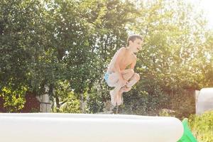 jongen jumping in de zwemmen zwembad in de tuin Bij zomer foto