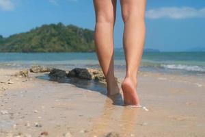 vrouw voeten lopen langzaam op tropisch zandstrand foto
