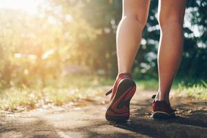 vrouw die loopschoenen draagt en op aard groene achtergrond loopt foto