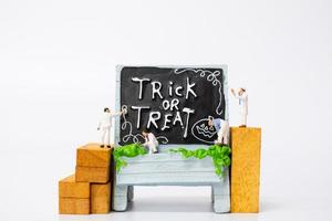 miniatuurmensen die halloween-decoraties van de partijsteun op een witte achtergrond, halloween-partijconcept kleuren foto