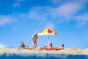 miniatuurmensen die op het strand, zomerconcept zonnebaden foto