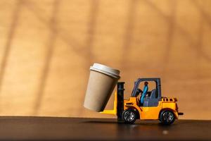 miniatuurpersoon en een kopje koffie voor onderweg, koffieleveringsconcept foto