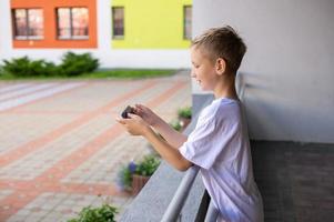 een jongen is staand Aan de straat met een telefoon foto