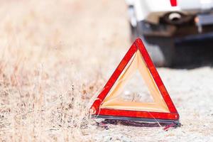 detailopname schot van de rood noodgeval hou op teken en gebroken wit auto Aan de langs de weg foto