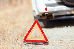 detailopname schot van de rood noodgeval hou op teken en gebroken wit auto Aan de langs de weg foto