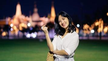 portret jong mooi Aziatisch vrouw glimlachen terwijl reizen Bij tempel van de smaragd Boeddha of wat phra kaew in nacht visie punt, Bangkok, Thailand. foto