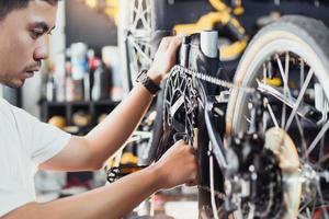 technicus maakt aanpassingen naar crankstel en repareren de schakelen Aan een vouwen fiets werken in werkplaats , fiets reparatie en onderhoud concept foto