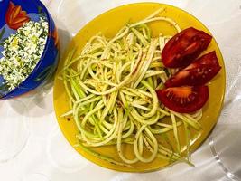 rauw veganistisch pasta met courgette en kers tomaten Aan een bord. vegetarisch gezond voedsel. foto