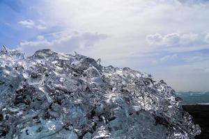 diamantstrand in ijsland met blauwe ijsbergen die smelten op zwart zand en ijs dat glinstert van zonlicht. foto