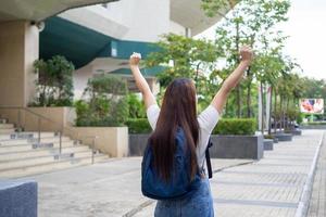 Aziatisch vrouw leerling ontspannen houding voelde heel gelukkig na school- gedurende de pauze. draag- een rugzak, klaar naar Gaan huis. foto