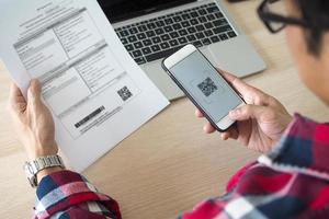 mannen betalen jaar- leven verzekering geld door bank toepassingen via smartphone. foto