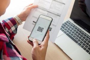 de butler is gebruik makend van een mobiel telefoon naar scannen de qr code voor de Bill door de app. handig, snel, is een optie van modern. foto