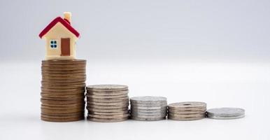 huis model- en munt Aan een wit achtergrond voor financiën, besparing en bank concepten foto