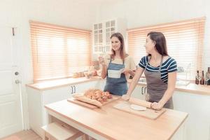 twee Kaukasisch Dames Koken pizza samen in de keuken. de concept van huisgemaakt voedsel en lgbt verhoudingen. familie en verscheidenheid concept. lgbt. foto