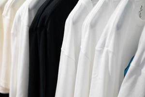 kleren Aan kleding rek. grijs t-shirt slijtage Aan hangers in kast of voorjaar schoonmaak concept. zomer huis garderobe. kleding hangende Aan een kleding rek in een winkel of huis kast. selectief focus. foto