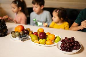 vier kinderen eten fruit in houten land huis Aan weekend. foto