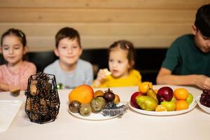 vier kinderen eten fruit in houten land huis Aan weekend. foto