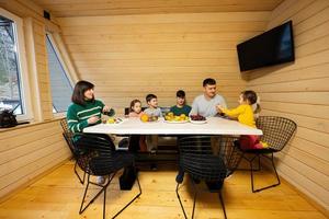 familie met vier kinderen eten fruit in houten land huis Aan weekend. foto