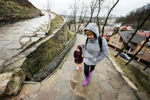 moeder en meisjes wandelen omhoog de nat pad naar een oude middeleeuws kasteel vesting in regen. foto