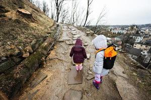 twee meisjes zussen wandelen omhoog de nat pad naar een oude vesting in regen. foto