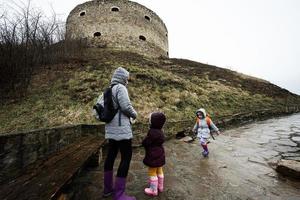 moeder en meisjes wandelen omhoog de nat pad naar een oude middeleeuws vesting in regen. terebovlia kasteel, Oekraïne. foto