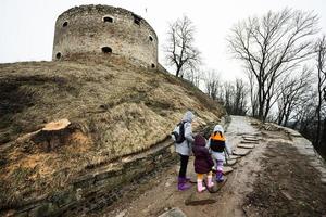 moeder en meisjes wandelen omhoog de nat pad naar een oude middeleeuws vesting in regen. terebovlia kasteel, Oekraïne. foto