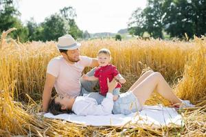 gelukkig jong familie met een jong zoon hebben pret in de zomer in de veld- foto