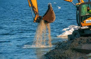 dnepropetrovsk, Oekraïne - 26.11.2021 graafmachine werken naar versterken de dijk. hydraulisch graafmachine werken Aan de rivier- bank. foto