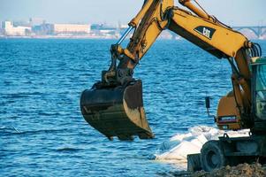 dnepropetrovsk, Oekraïne - 26.11.2021 graafmachine werken naar versterken de dijk. hydraulisch graafmachine werken Aan de rivier- bank. foto