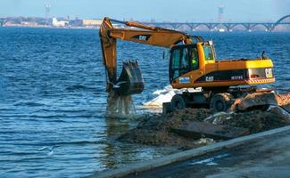 dnepropetrovsk, Oekraïne - 26.11.2021 graafmachine werken naar versterken de dijk. hydraulisch graafmachine werken Aan de rivier- bank. foto