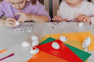 kinderen versieren dummies van wit eieren, stok stickers met verschillend emoties, studie van emoties foto