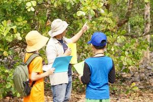 Aziatisch Mens leraar is onderwijs botanisch planten met studenten. buitenshuis klas. zomer kamp werkzaamheid. concept, aan het leren door aan het doen. actief leren.echt leven beleven. natuur vragenlijst. foto