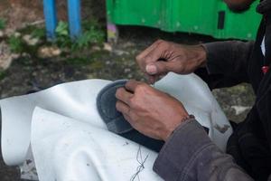 selectief focus Aan sandalen dat zijn wezen gerepareerd door naaien gebruik makend van draad en naalden, deze werk is gebeld in Indonesië een tukang Sol apart, zacht focus foto