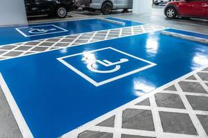 auto parkeren veel Gereserveerd voor gehandicapten bestuurder in supermarkt of boodschappen doen winkelcentrum. auto parkeren ruimte voor gehandicapt mensen. rolstoel teken verf Aan parkeren Oppervlakte. blauw en wit gehandicapten parkeren kavel. foto