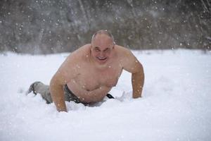 een volwassen Mens is gehard door sneeuw Aan een winter dag. een naakt Mens leugens in de sneeuw. foto
