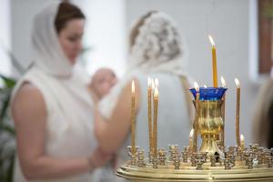 wazig rite van orthodox doop tegen de achtergrond van brandend kaarsen. foto